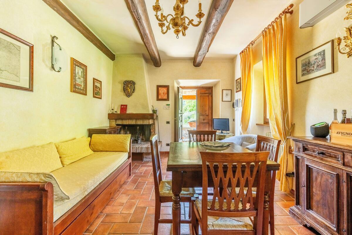A dining area with a wooden table, chairs, a sofa, and a fireplace.