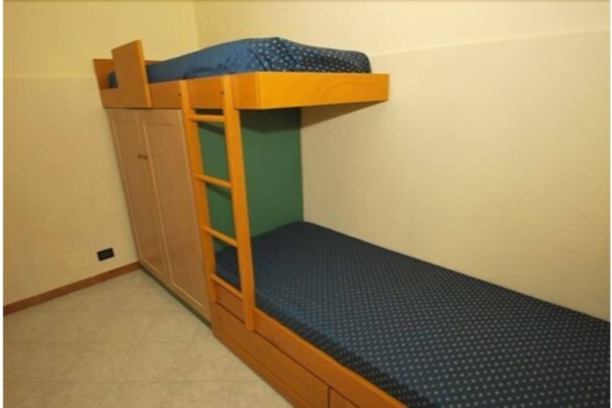 A bunk bed with a wooden frame and a blue mattress.