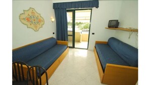 A room with two blue sofas, a small table, and a chair. - Alessidamo Club Metaponto (Bernalda)