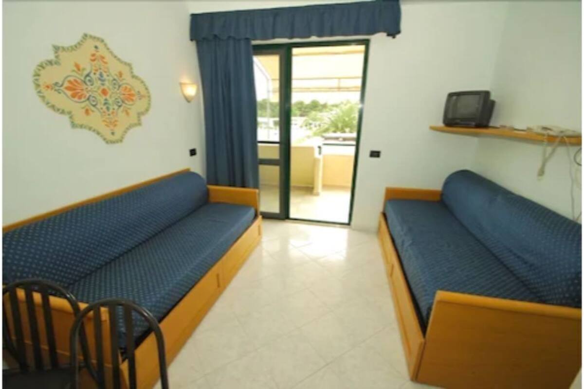 A room with two blue sofas, a small table, and a chair.
