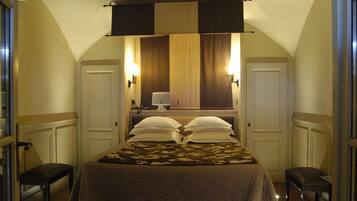 Habitación de hotel con cama, dos mesitas de noche, un escritorio con lámpara y un ventanal con cortinas.