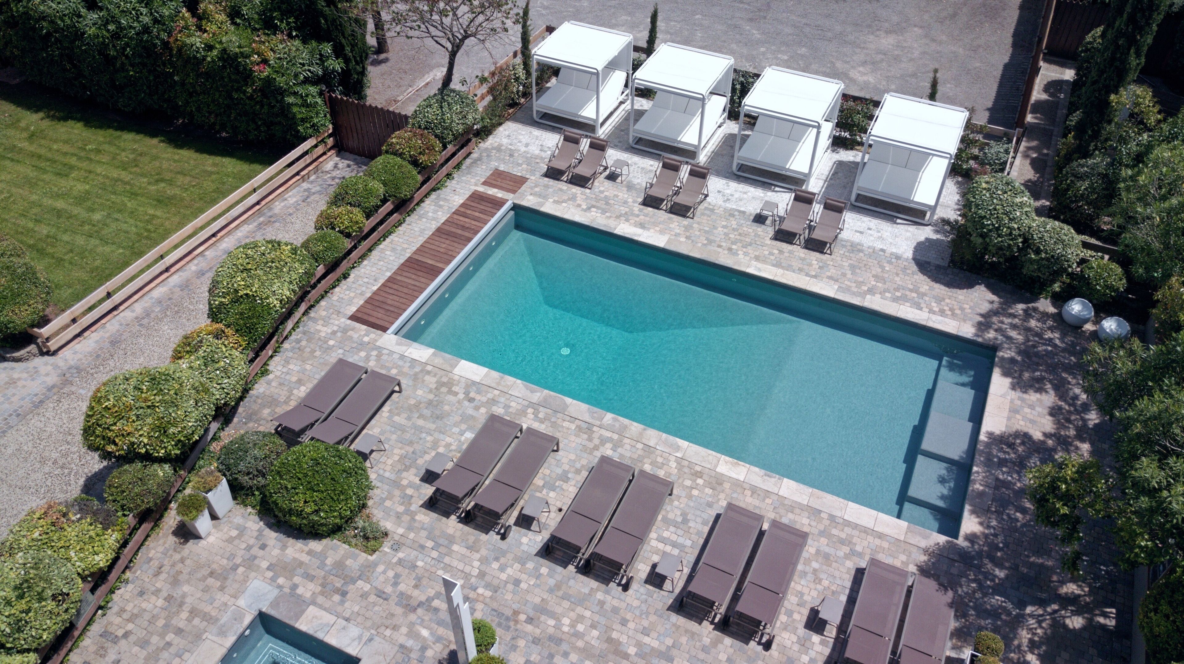 Vista aérea de una piscina rectangular con sillones y tumbonas alrededor.