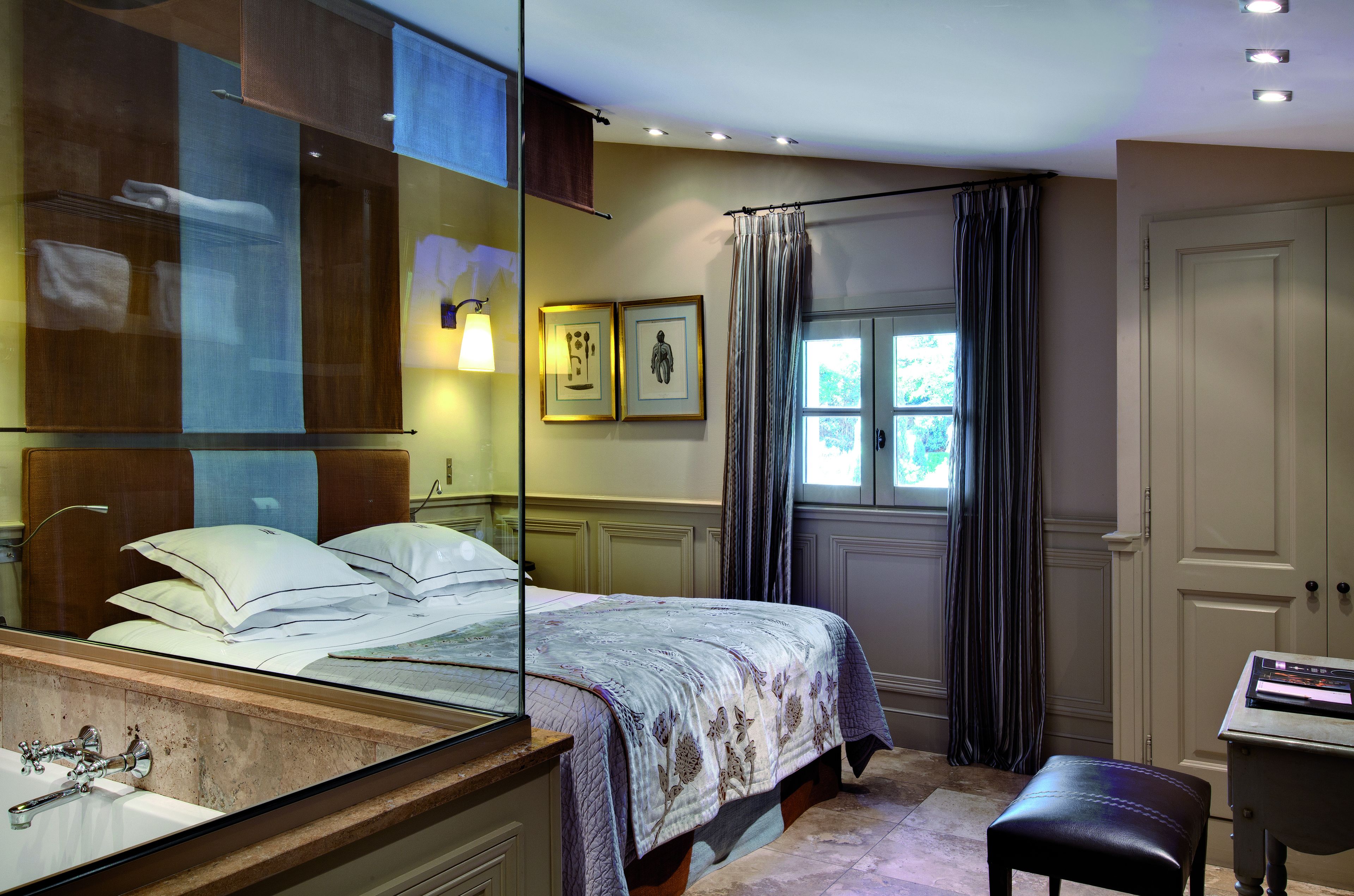 A bedroom with a bed, a mirror, a desk, and a window with curtains.