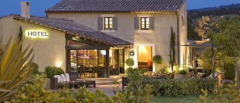 A hotel with a patio area, outdoor seating, and a well-lit entrance.