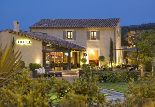 A hotel with a patio area, outdoor seating, and a well-lit entrance.