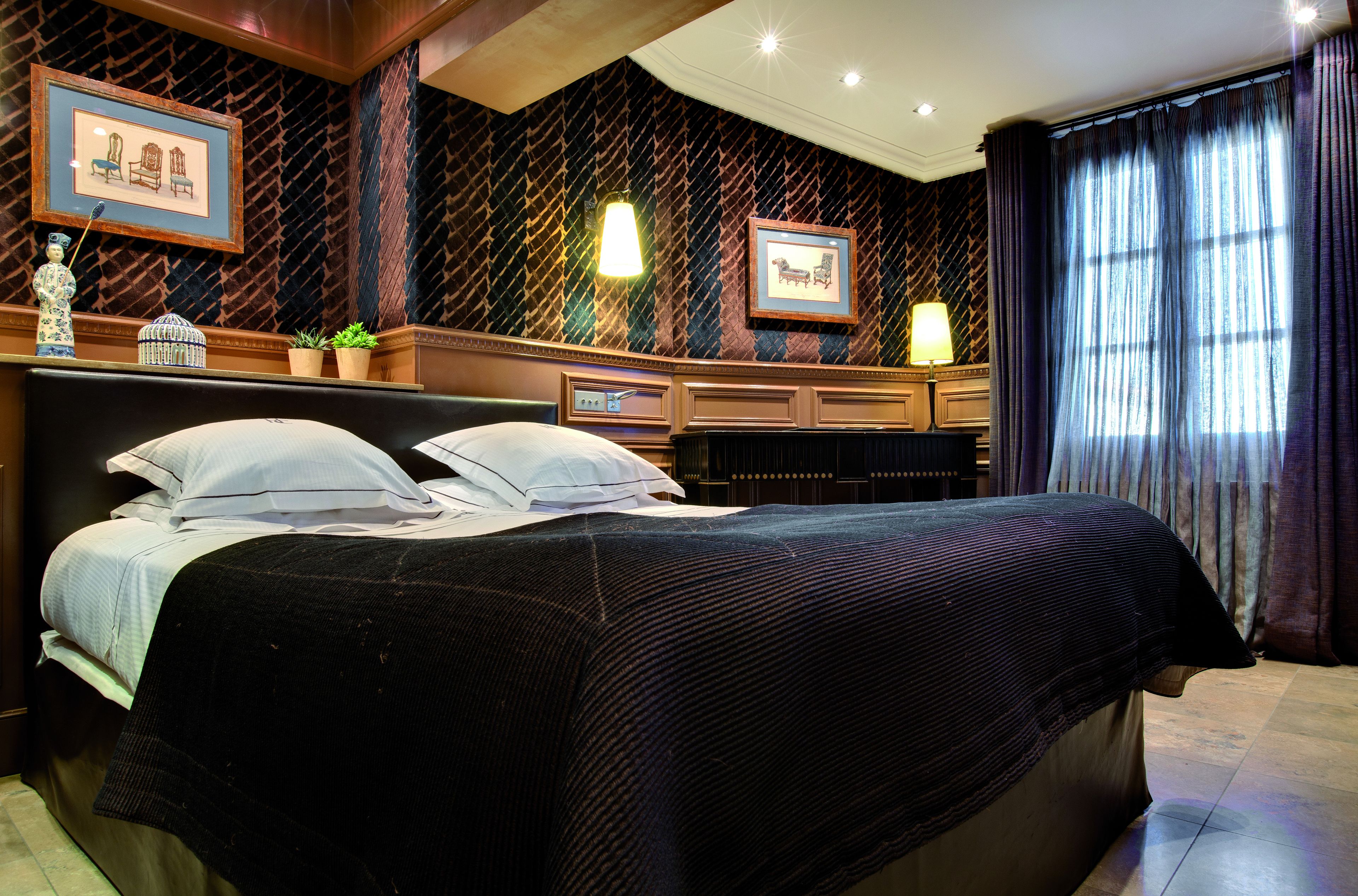 Une chambre d’hôtel avec un grand lit, une commode, un bureau et une fenêtre avec des rideaux.