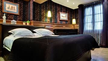 Une chambre d’hôtel avec un grand lit, une commode, un bureau et une fenêtre avec des rideaux.