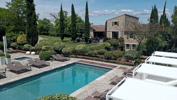 A swimming pool with lounge chairs, a well-maintained lawn, and a building with a tiled roof.