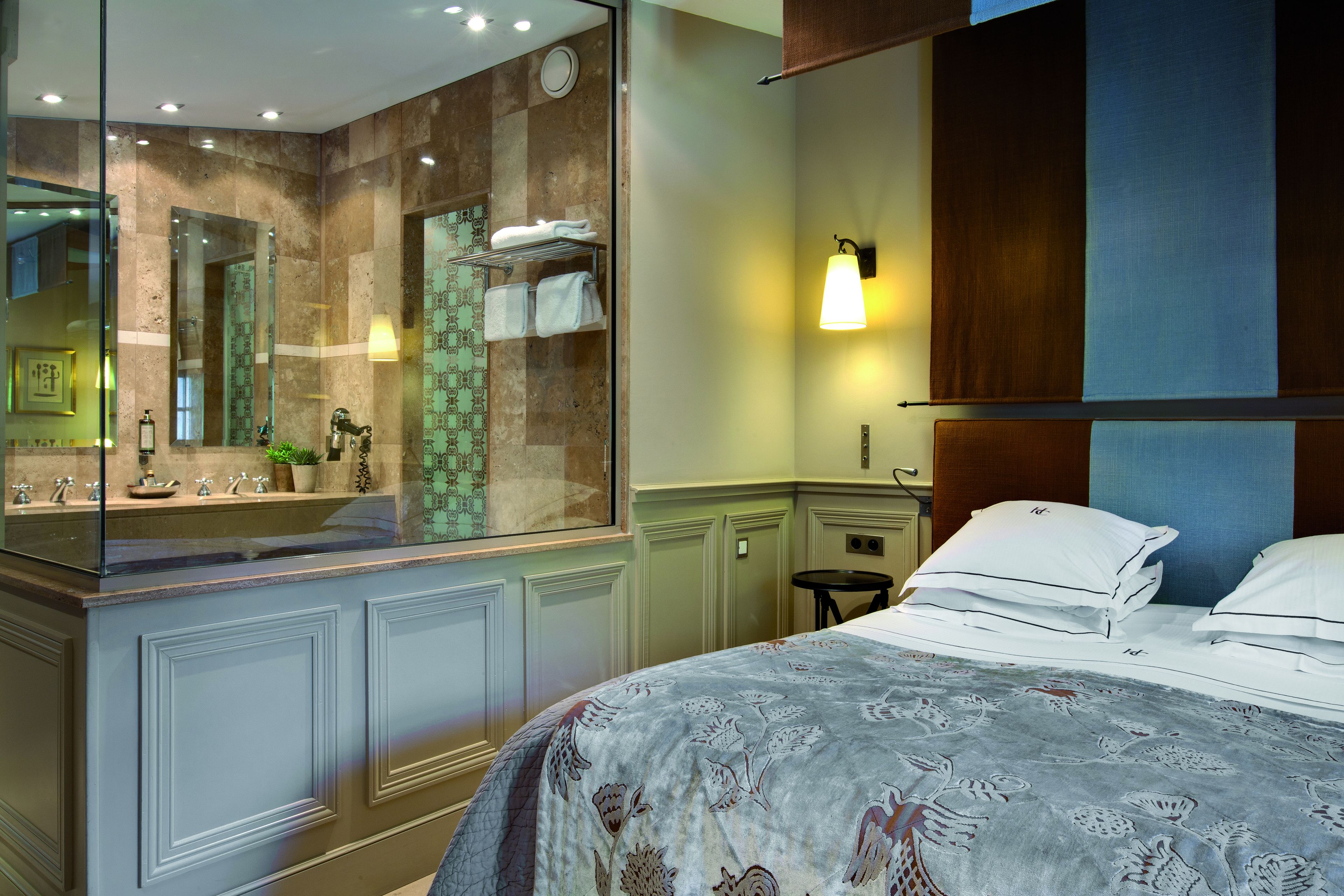 Ein Hotelzimmer mit einem großen Bett, einem Badezimmer mit Duschkabine und einem Spiegel, der das Badezimmer widerspiegelt.