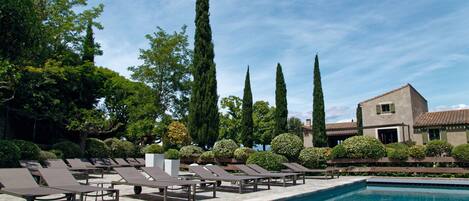 A pool area with lounge chairs and a building in the background.