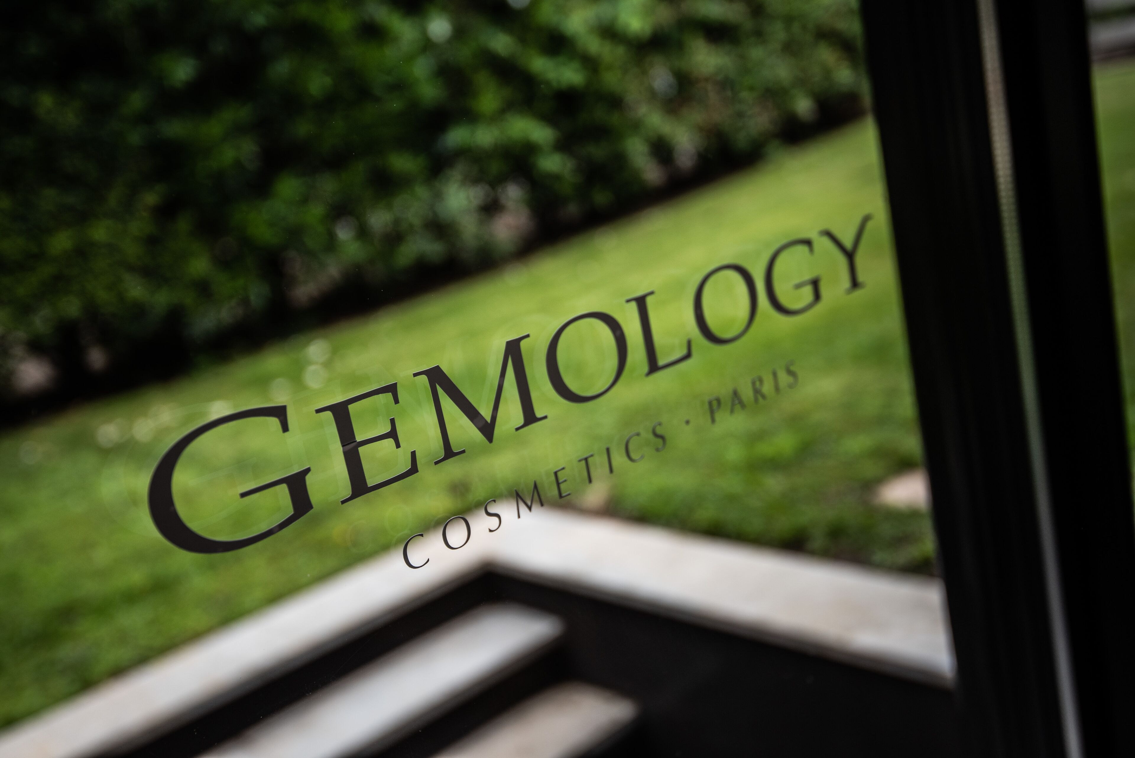 Ein Schild mit dem Aufdruck "GEMOLOGY COSMETICS PARIS" in einem Schaufenster.