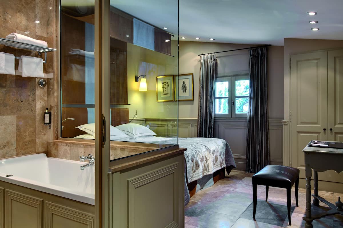 A bathroom with a large mirror, a bathtub, a sink, and a vanity.