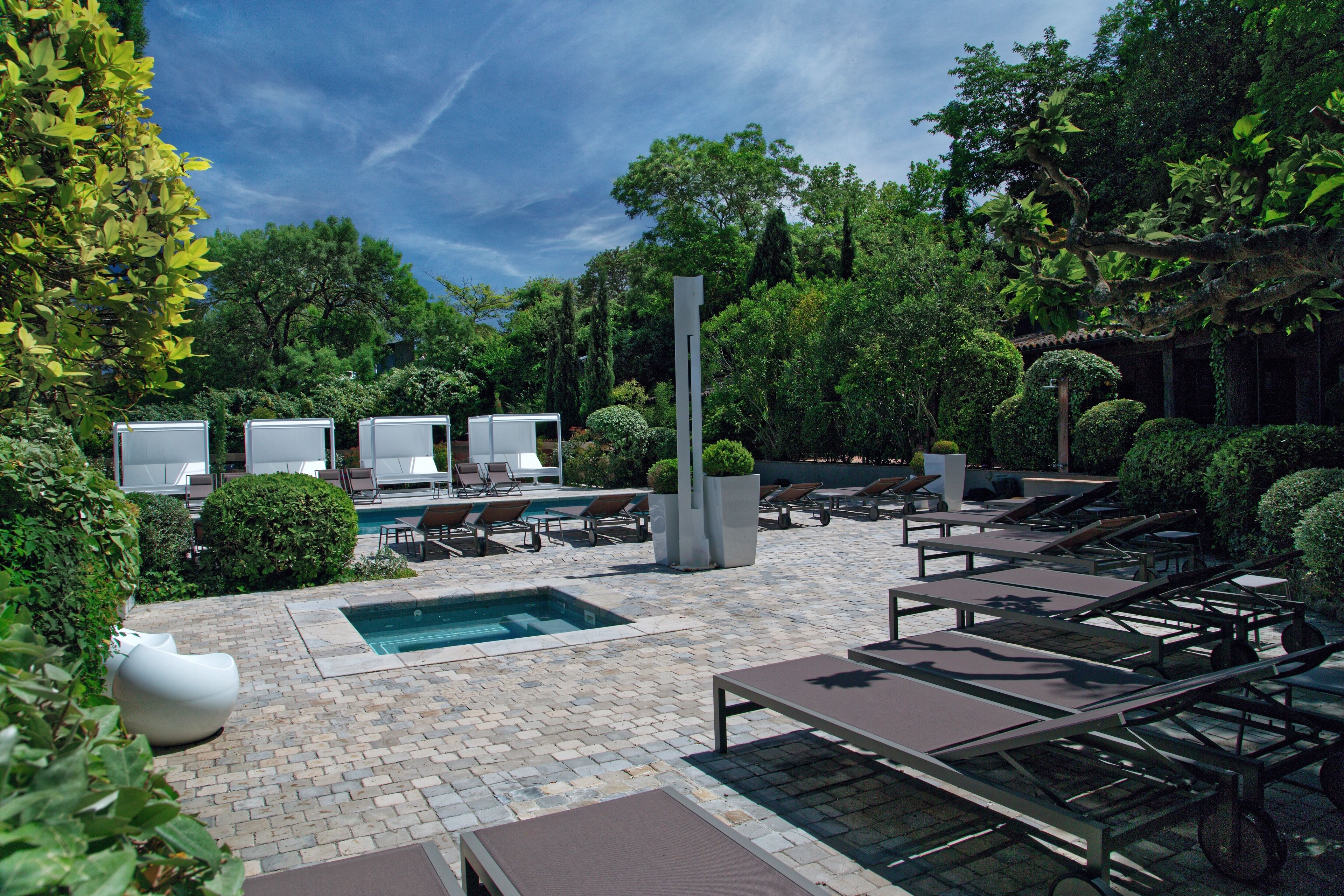 A poolside area with lounge chairs, a swimming pool, and a modern sculpture.