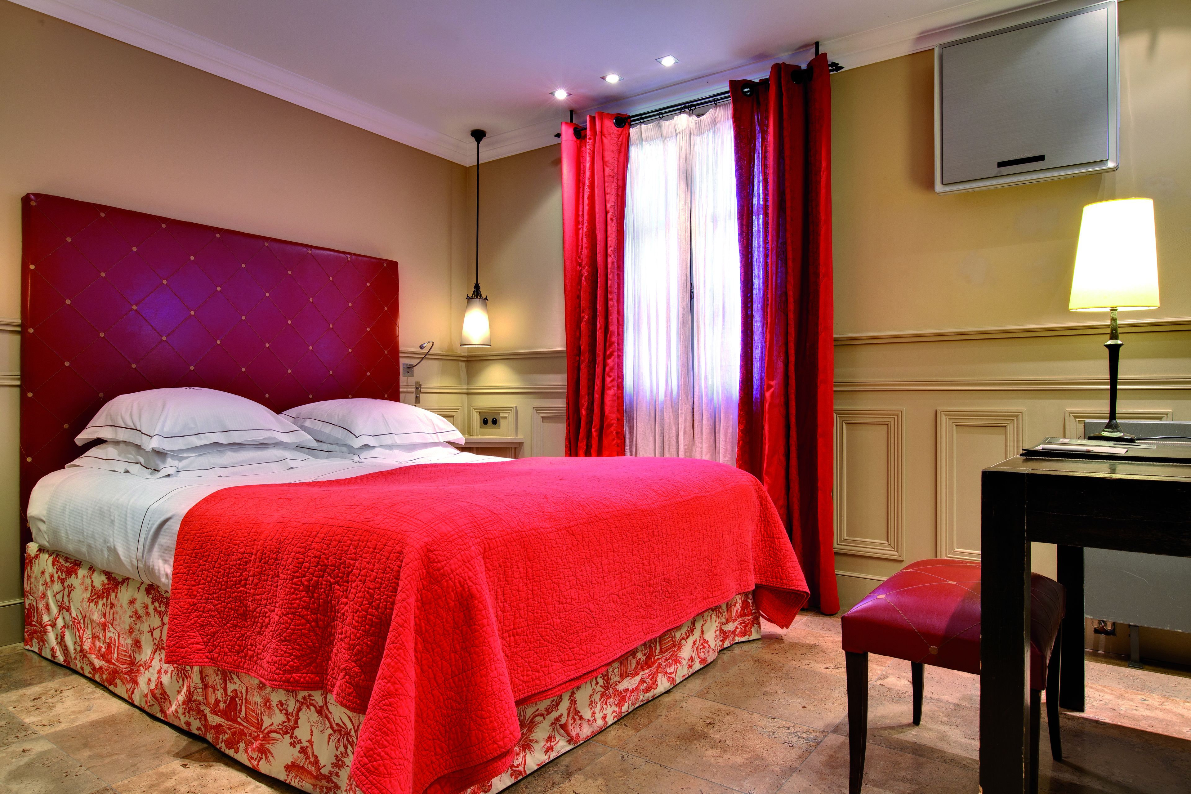 A hotel room with a large bed, a desk, and a chair.