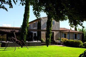 Una casa con un patio, césped y una escultura.
