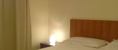 Una habitación de hotel con cama, mesita de noche y un cuadro en la pared.