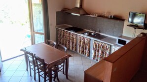 Une cuisine de taille réduite comprenant un coin repas, un téléviseur et une fenêtre.