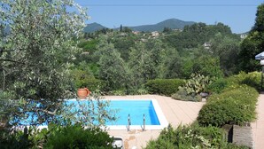 Une piscine rectangulaire à l’eau d’un bleu cristallin, entourée d’une végétation luxuriante et dominée par un paysage montagneux.