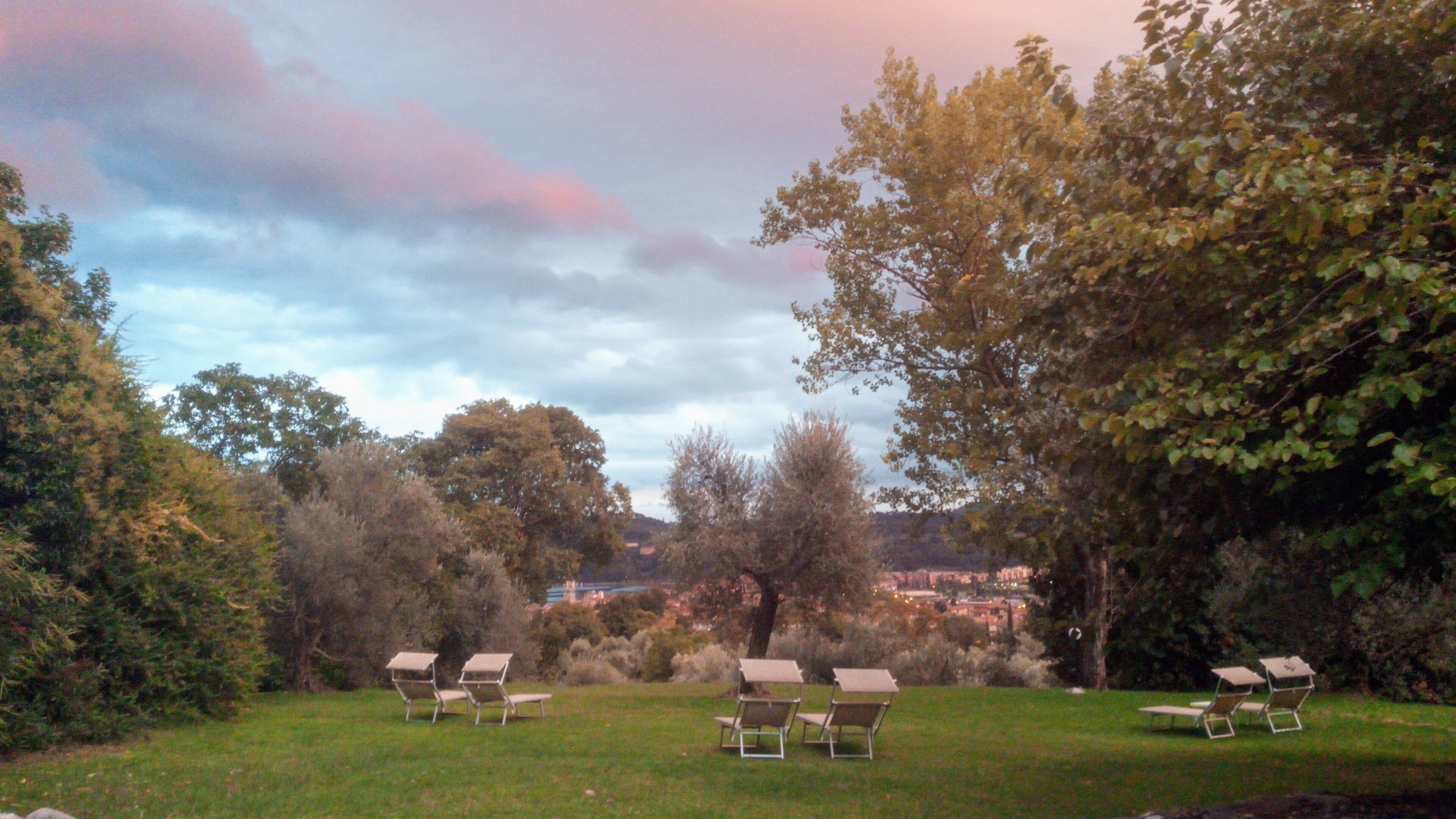 Ein Garten mit vier Liegestühlen und Blick auf eine Stadt in der Ferne.