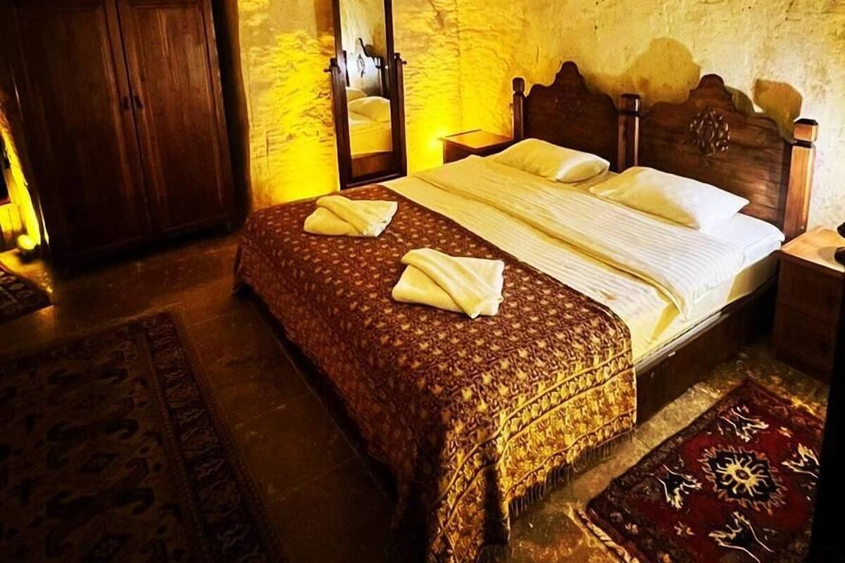 A bedroom with a wooden bed, a wardrobe, a mirror, and a patterned rug.