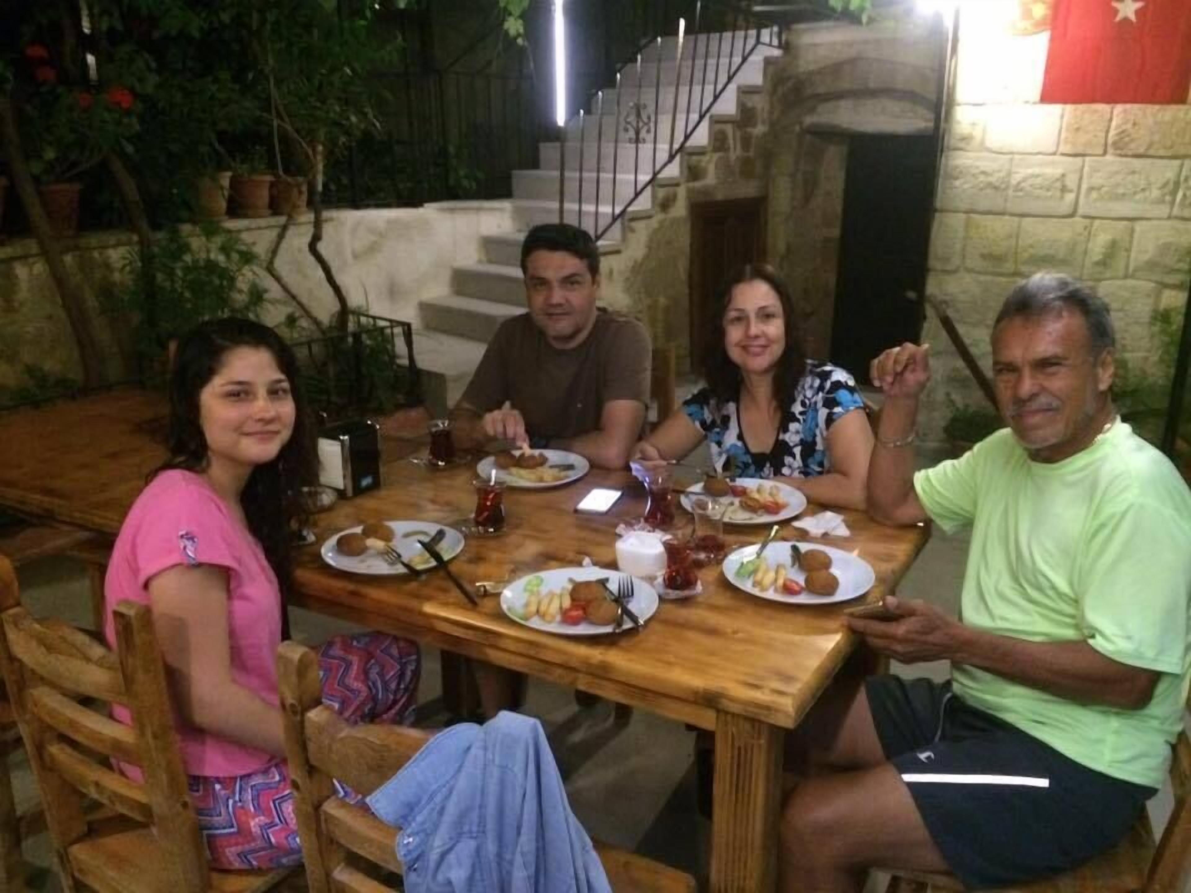 Un grup de persones dinant a una taula de fusta amb diferents plats.