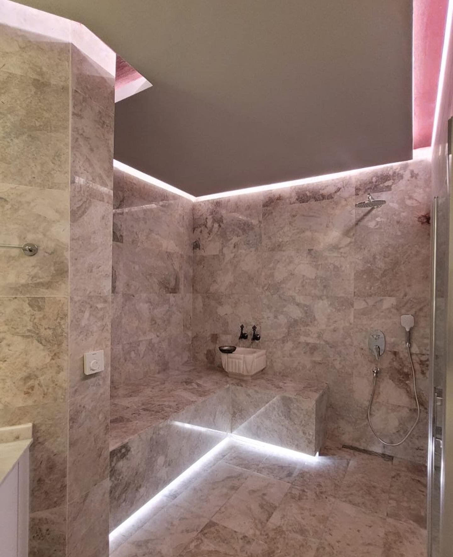 Un baño moderno con una bañera independiente, una ducha de mano y un grifo empotrado en la pared.