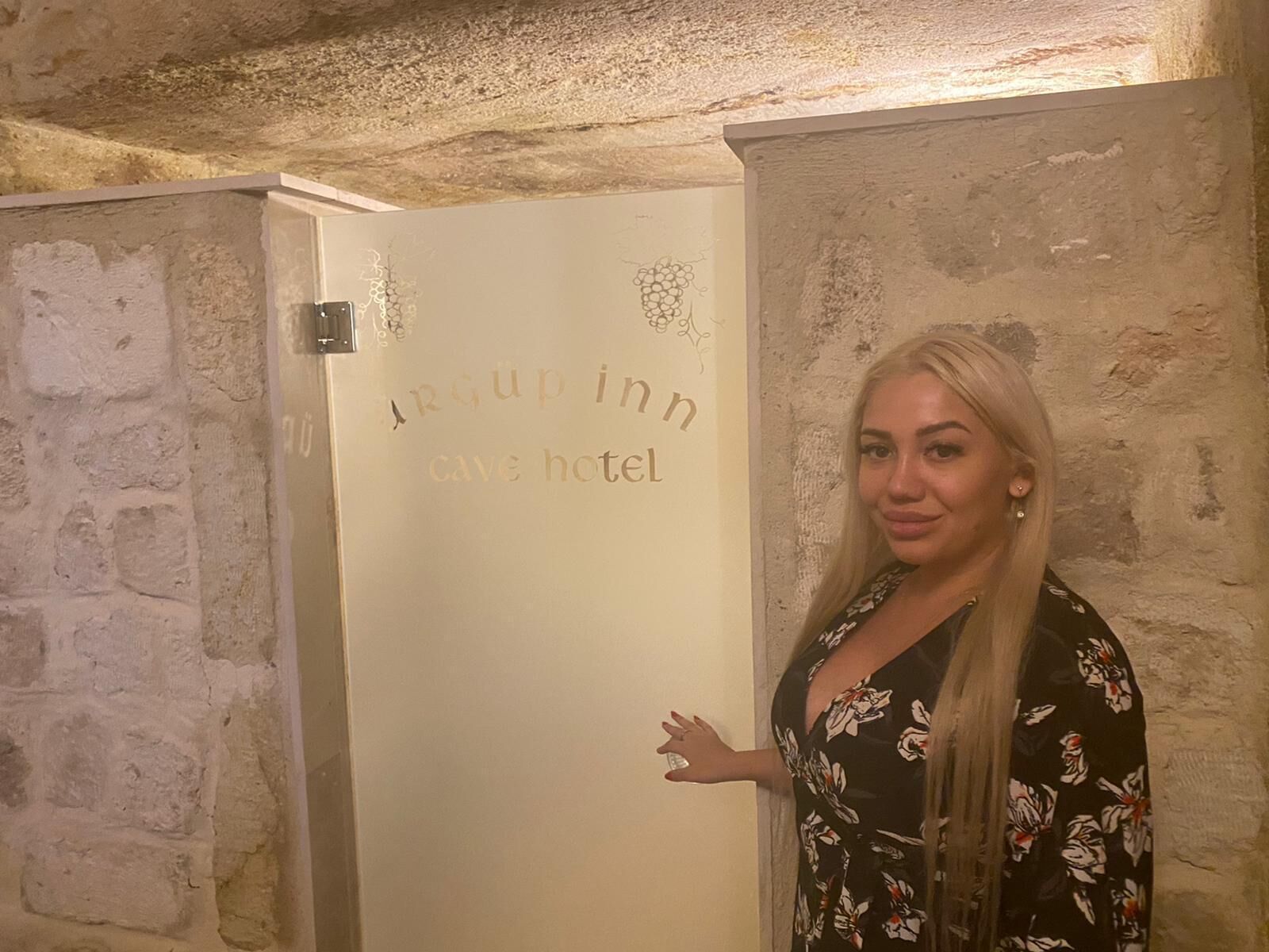 A woman standing in front of a door with the inscription "Argup inn cave hotel".