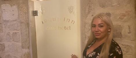 A woman standing in front of a door with the inscription "Argup inn cave hotel".