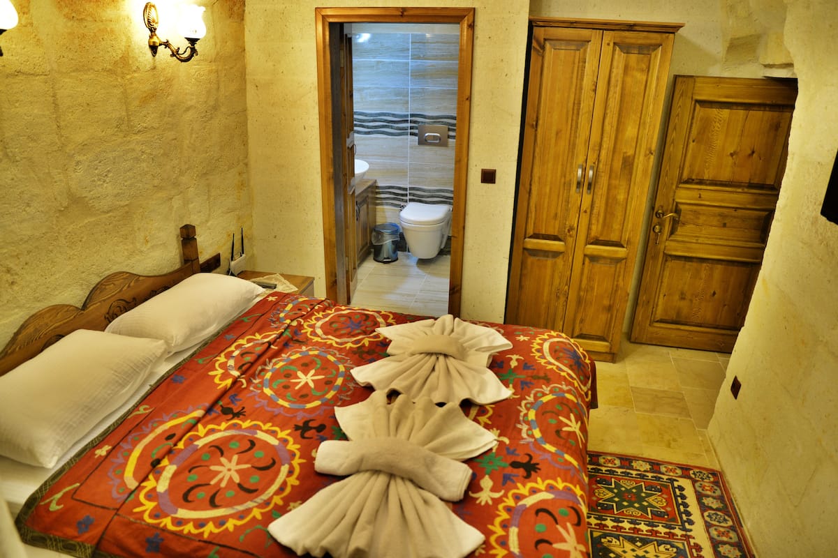 A room with a bed, a wooden door, and a view of a bathroom through an open door.