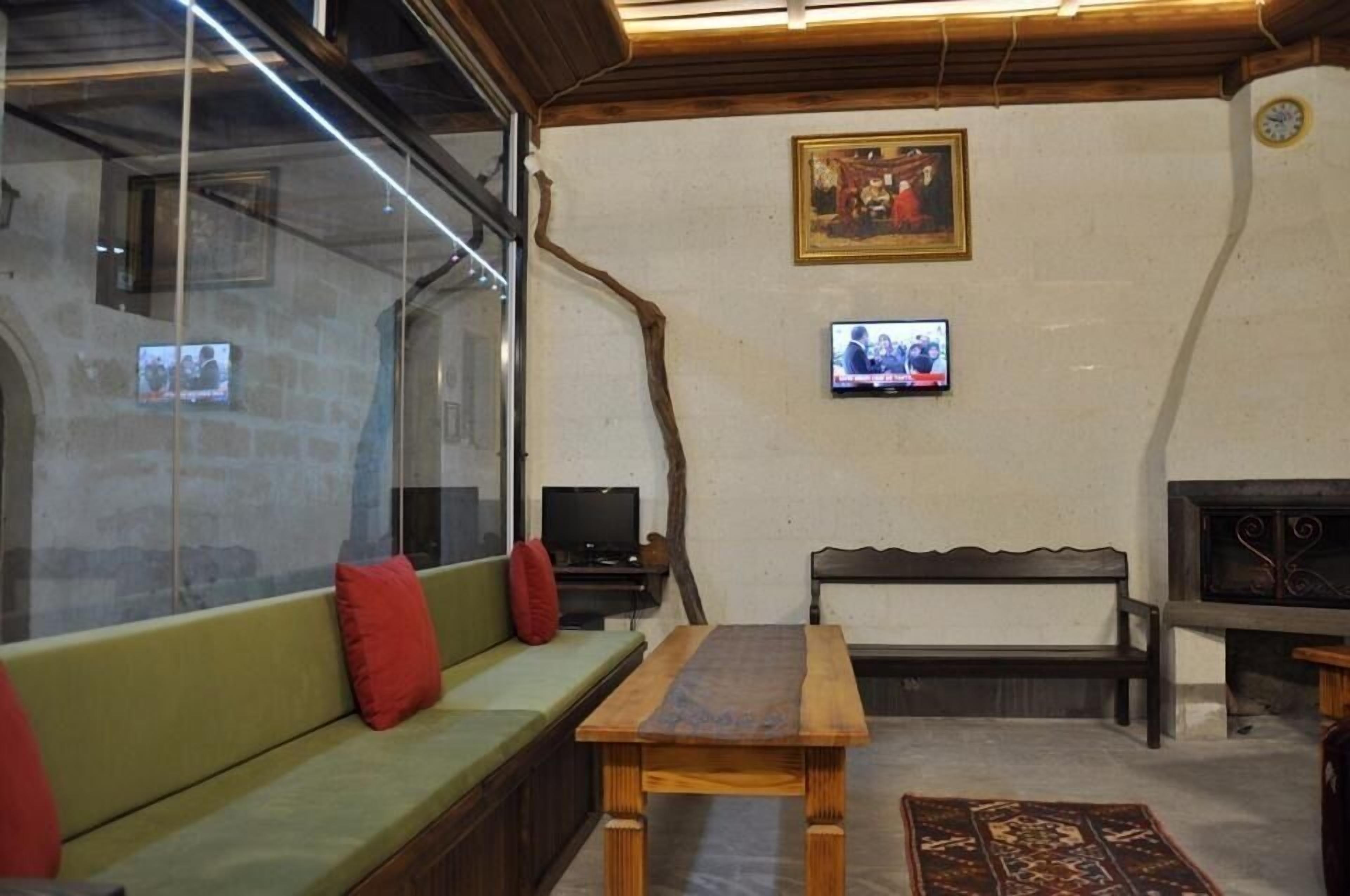 A cozy living room with a green sofa, a wooden table, a television, and a fireplace.