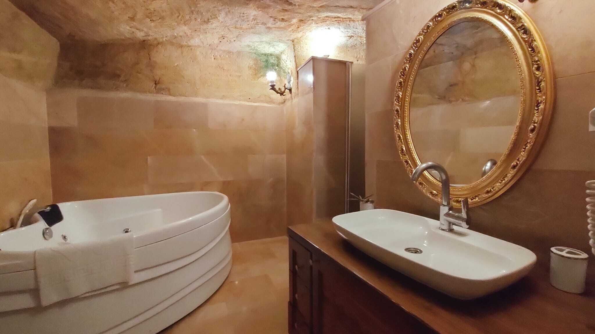 Un baño con bañera, lavamanos, espejo y toallero.