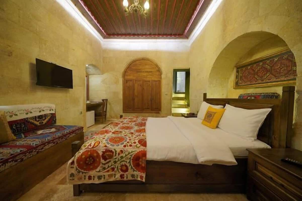 A bedroom with a wooden bed, a sofa, a television, and a chandelier.