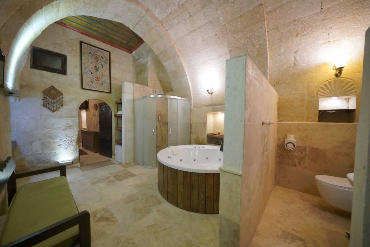 A stone-walled bathroom with a freestanding bathtub, a toilet, and a shower enclosure.