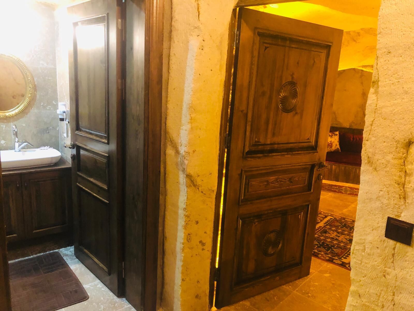 Un baño con lavamanos, espejo y puerta de madera.