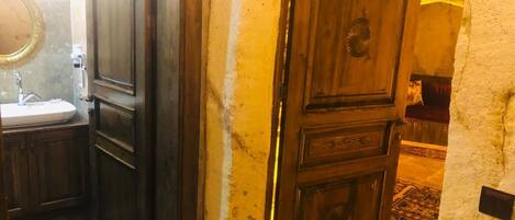Un baño con lavamanos, espejo y puerta de madera.