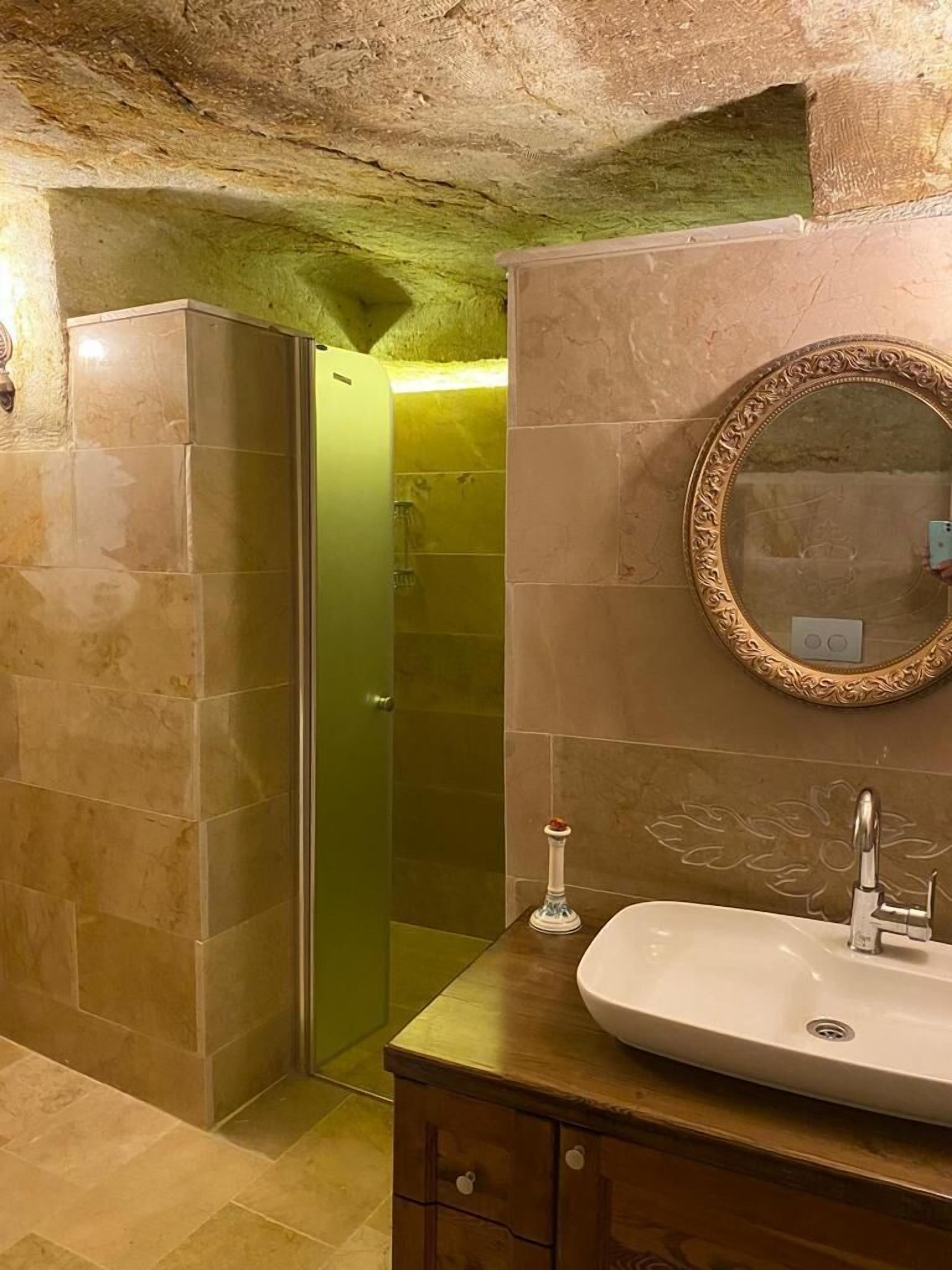 A bathroom with a large mirror, a sink, and a shower.