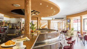 Zona de bar con mostrador curvo, asientos y una variedad de botellas.