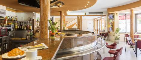 A bar area with a curved counter, seating, and a variety of bottles.