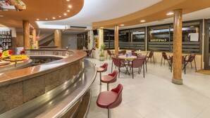 Una cafetería moderna con una barra curva, zona de asientos y amplios ventanales.