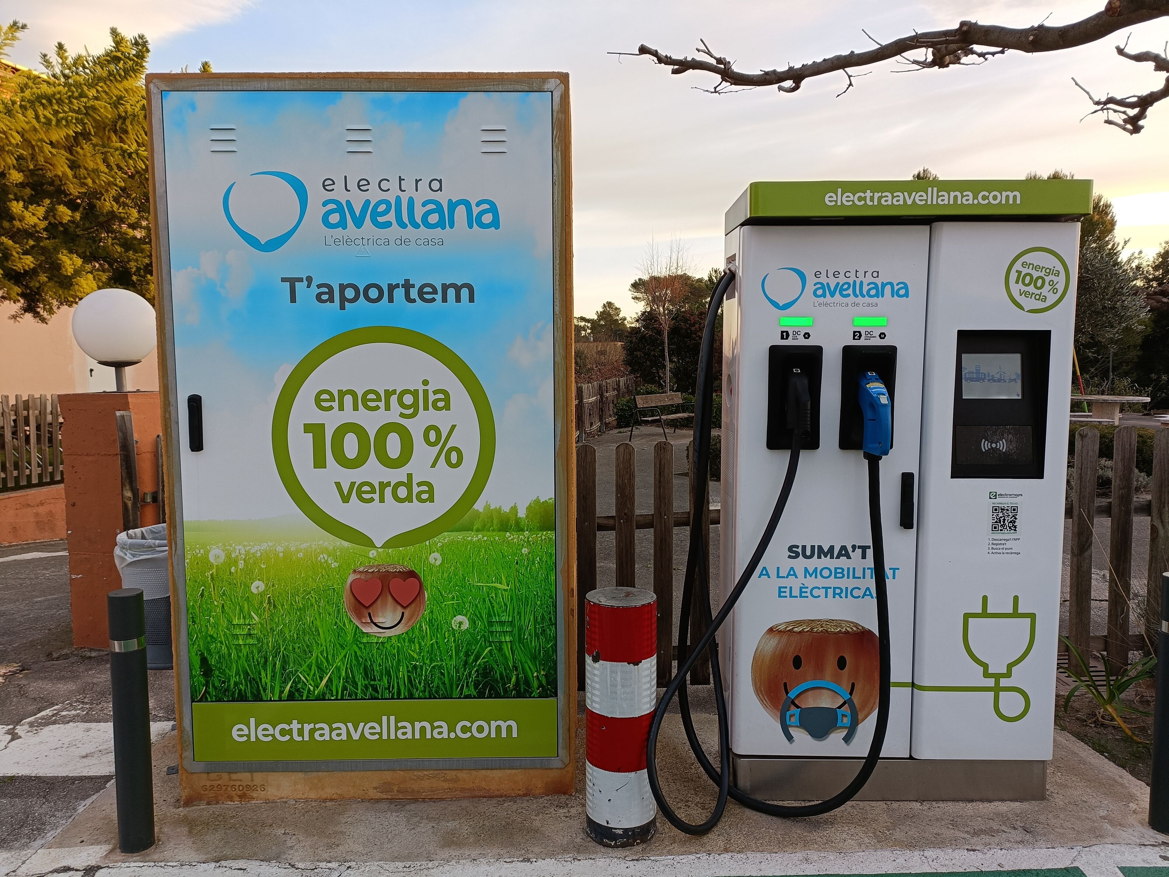 An electric vehicle charging station with a sign advertising 100% green energy.