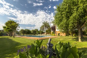 Un jardin bien entretenu, doté d’une piscine, et entouré d’une végétation luxuriante et d’arbres.