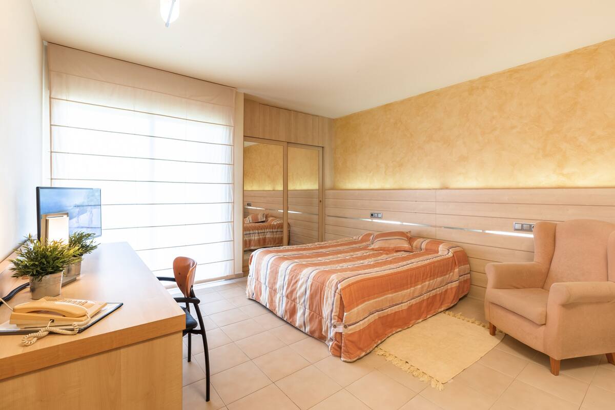 Ein modernes Schlafzimmer mit einem großen Bett, einem Schreibtisch mit Telefon und einem Sessel.