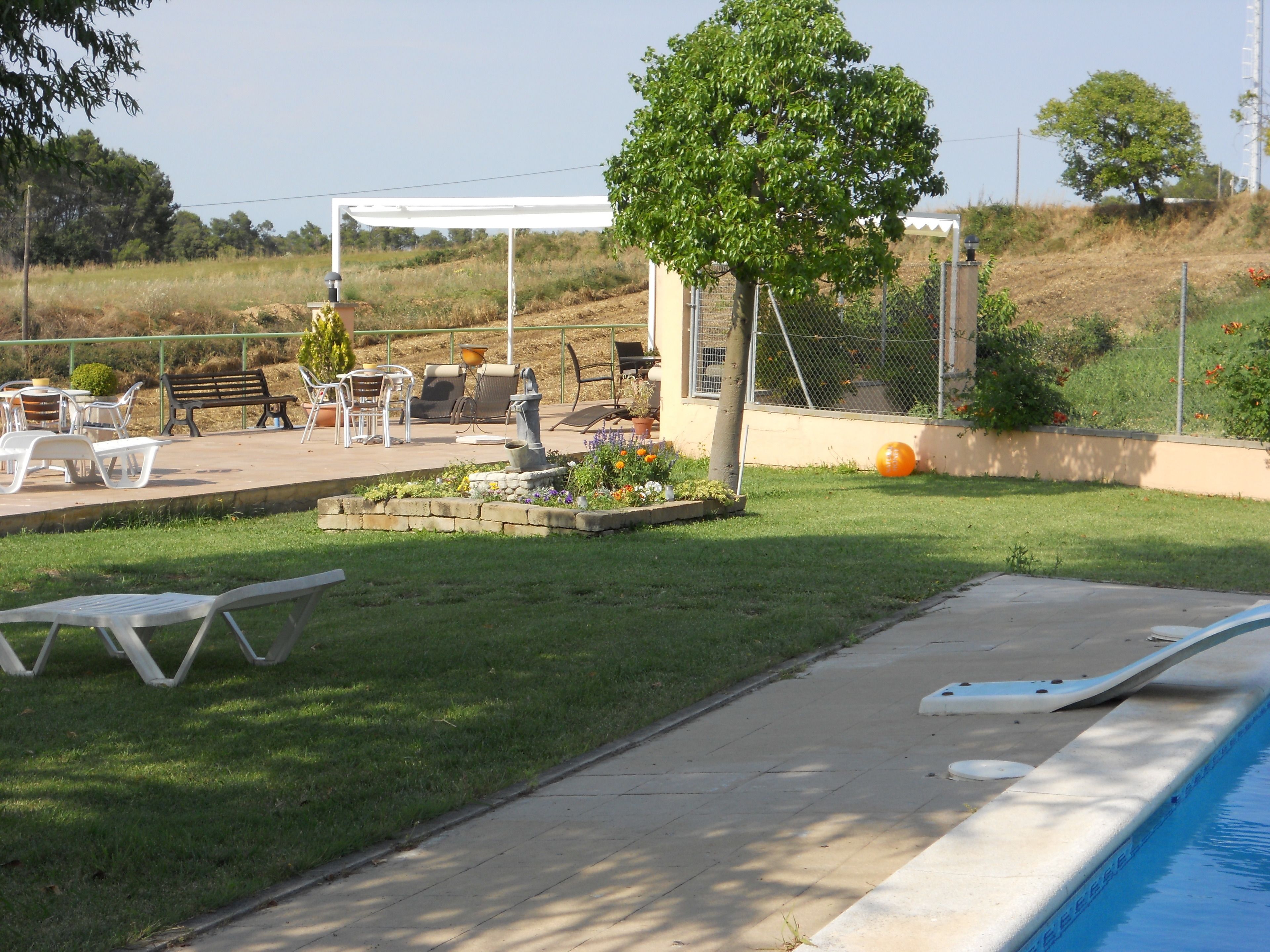 A backyard with a swimming pool, a patio with outdoor furniture, and a garden area.