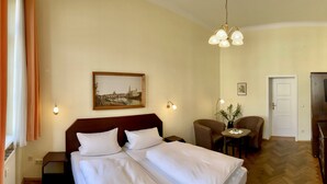 A hotel room with two beds, a desk with a chair, a television, and a painting on the wall. - Apartmenthaus Stadt Metz (Dresden)