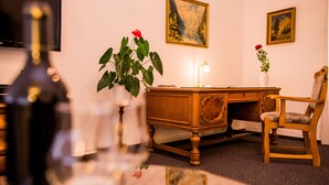 A room with a wooden desk, a chair, a lamp, a vase with a red flower, and a painting on the wall. - Apartmenthaus Stadt Metz (Dresden)