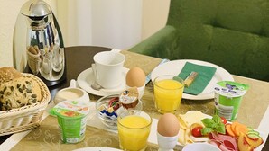 A breakfast table set with plates, cups, a basket of bread, a coffee pot, and various breakfast items. - Apartmenthaus Stadt Metz (Dresden)