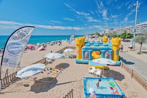 A beach with inflatable play structures, umbrellas, and a pool area. - Hotel Sabiote (Pineda de Mar)