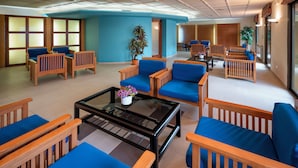A spacious lobby with multiple seating areas, including wooden chairs and sofas with blue cushions, arranged around a central coffee table. - Hotel Sabiote (Pineda de Mar)