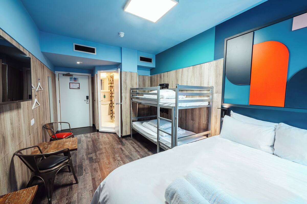 A hotel room with bunk beds, a wooden desk, and a shower area.