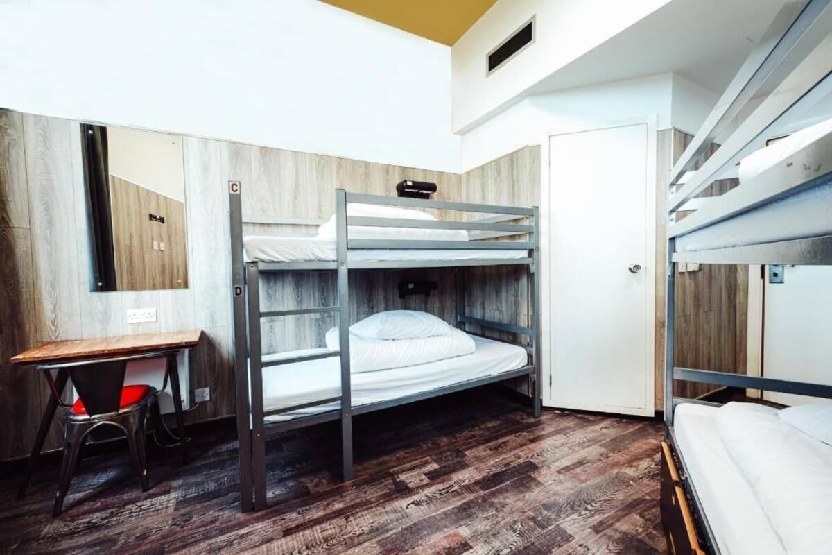 A bunk bed room with a desk and chair, wooden walls, and a door.